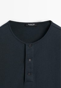 Dunkelblaues T-Shirt mit Rundhalsausschnitt und drei schwarzen Knöpfen an der Knopfleiste sowie einem Etikett mit der Aufschrift "Massimo Dutti Made in Portugal" innen am Kragen.