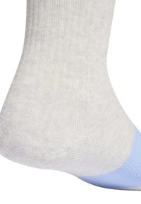 Primo piano di una calza bianca con texture a coste e una sezione della punta in azzurro chiaro su un piede, che mette in evidenza i dettagli del tessuto e delle cuciture.