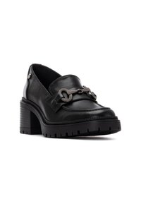 Mocassini neri in pelle con tacco, caratterizzati da una punta arrotondata, una superficie testurizzata e dettagli ornamentali a catena sul davanti. Suola spessa con battistrada.