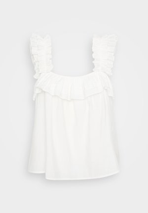 Bijela pamučna majica s naboranim naramenicama i slojevitim volanom na izrezu. Labav kroj s glatkom, laganom teksturom.