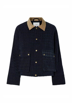 Marinblå quiltad jacka med en beige manchesterkrage, två framfickor och guldtryckknappar. Har en texturerad tyg och en avslappnad passform.