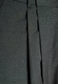 Melns audums ar teksturētu virsmu un smalkām metāliskām diegu pērlītēm. Materiāls ir savilkts krokās ar gludu jostasvietu un šūtu dizainu.