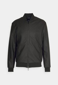 Giacca bomber nera con una texture trapuntata, chiusura con zip, e polsini e orlo a costine. Presenta tasche laterali e un colletto alto.