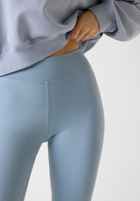 Leggings bleu clair taille haute en matière extensible, présentant des coutures plates et une texture lisse et mate.