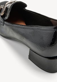 Mocassin en cuir verni noir avec petit talon carré et détail boucle argentée sur le dessus, vu de l'arrière.