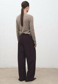 Suéter de cachemira beige y pantalones de pierna ancha burdeos oscuros. Textura suave, diseño elegante y un look minimalista.