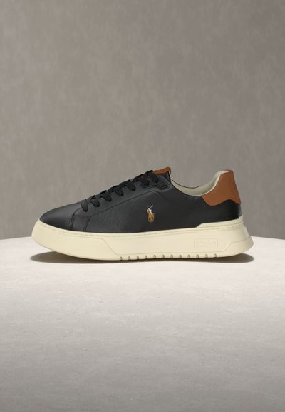 Baskets en cuir noir avec semelle crème, languette de talon marron, lacets noirs et petit logo brodé d’un joueur de polo sur le côté.