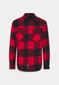 Camicia a scacchi rossa e nera con maniche lunghe, chiusura con bottoni frontale, due tasche sul petto e un tessuto morbido e testurizzato.