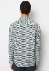 Langärmliges Hemd aus leichtem Stoff mit einem geometrischen Muster in Marineblau und Creme. Weiche Textur, spitzer Kragen, geschwungener Saum.