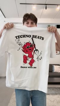Camiseta de algodón blanca con un diablillo de dibujos animados rojo con gafas de sol, sosteniendo un tridente. El texto dice "TECHNO BEATS Baila conmigo" en negro.