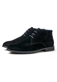 Bottes chukka en daim noir avec un bout arrondi, quatre œillets et des lacets bleus contrastants. Semelle en caoutchouc avec un détail de marque discret.