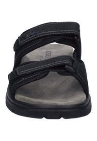 Zwarte slip on sandalen met twee verstelbare klittenbandstraps, een gevoerde grijze binnenzool en een gestructureerde rubberen buitenzool voor grip.