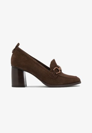 Scarpa con tacco alto in suede marrone, con punta rotonda, una fibbia decorativa e un tacco in legno impilato. Texture liscia con dettagli di cucitura.