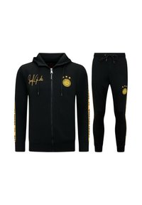 Zwarte sweatshirt met capuchon en rits, voorzien van gele accenten en logo. Gecombineerd met zwarte broek, beide van zachte stof met een slanke pasvorm.