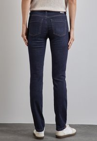 Mörkblå denim skinny jeans med en slät yta, midjehöjd, bakfickor och subtila sömdetaljer. Bärs med vita sneakers.