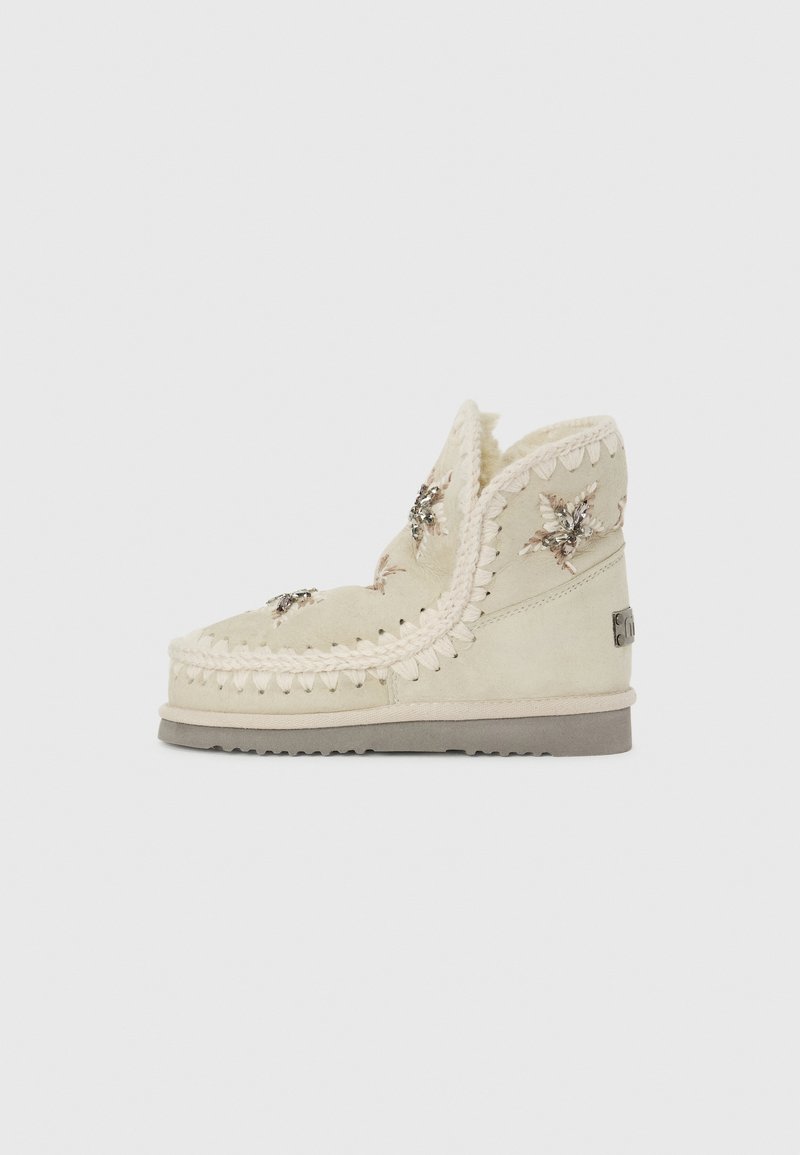 Lyse beige ankelstøvler lavet af ruskind med dekorativ syning, faux fur foring og udsmykkede blomsterdetaljer foran. Gummisål.