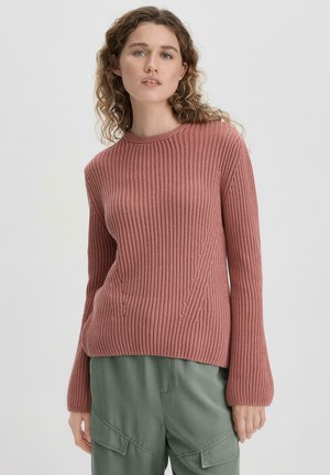 Rosa gerippter Strickpullover mit rundem Ausschnitt, langen Ärmeln und lockerem Schnitt, kombiniert mit olivgrünen Cargo-Hosen.