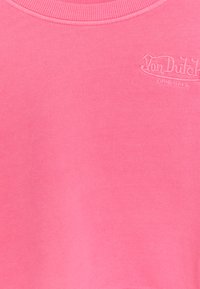 Roza pulover s kapuco z ribanim izrezom in majhnim vezenim logotipom "Von Dutch ORIGINALS" na prsih. Material izgleda mehak in teksturiran.