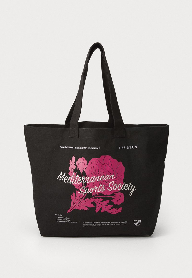 Svart lerret tote-bag med rosa blomsterdesign og hvit tekst som sier "Mediterranean Sports Society." Har to solide håndtak og romslig innvendig.