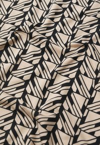 Tejido negro y beige con un patrón geométrico de líneas y formas entrelazadas, con una textura suave y un leve estiramiento.