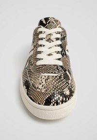 Baskets à lacets avec un motif texturé en peau de serpent noir et beige, dotées d'une semelle en caoutchouc blanc et de lacets blancs classiques.