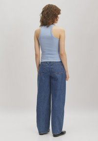 Helles Blau, geripptes Tanktop mit breiten Schulterträgern, kombiniert mit hoch taillierten, locker geschnittenen blauen Jeans aus Denim mit Gesäßtaschen.