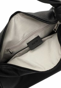 Zwarte leren handtas met een textuur en een beige stoffen binnenkant, voorzien van een ritsvak en een label. Ritsluiting bovenaan.