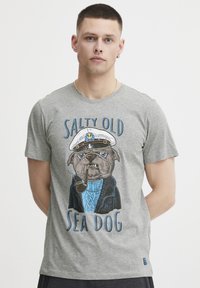 Grå bomull t-skjorte med et grafikk av en mops i kapteinslue, som r�øyker en pipe, med teksten "SALTY OLD SEA DOG" i blått.