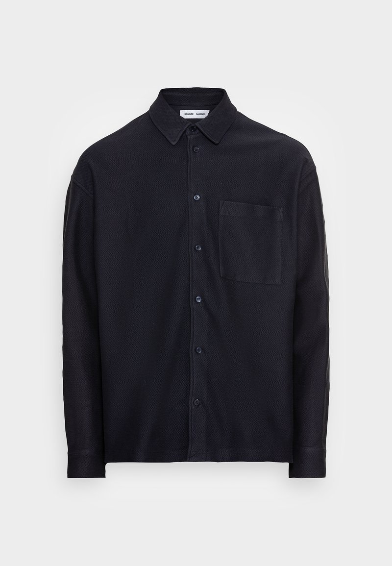 Maglietta blu navy con tessuto testurizzato, dotata di colletto, tasca frontale e maniche lunghe. Design semplice con bottoni scuri.