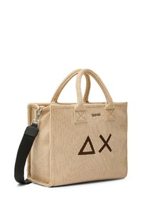 Borsa a spalla in corduroy beige con due manici superiori e una tracolla nera rimovibile. Presenta loghi geometrici marrone scuro e dettagli di cuciture a zigzag.