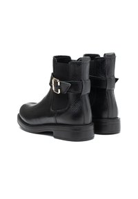 Botas de tobillo de cuero negro con un acabado texturizado. Presentan un panel lateral elástico y una hebilla metálica decorativa. Diseño de suela plana.