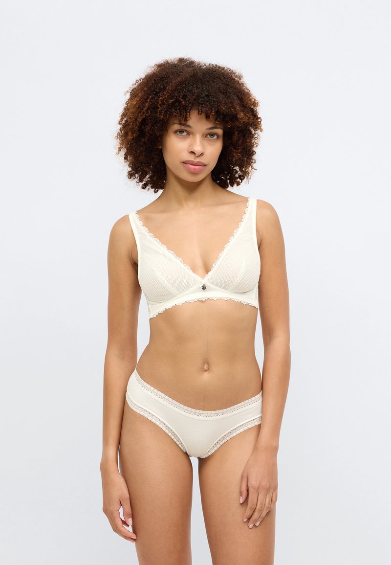 Κρεμ μπραζίλ κιλότ και ασορτί εσώρουχα από μαλακό ύφασμα, με δαντελένιες λεπτομέρειες και μικρό κεντρικό κουμπί. Κλασικός, λείος σχεδιασμός.
