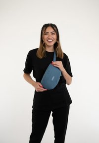 Tökéletes zöld, szövet övtáska cipzárral és állítható pánttal. Téglalap alakú, sima textúrájú, elöl márka címkével.