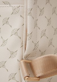 Strukturert hvit veske med et subtilt bladmønster, med beige detaljer og en metallisk gull hardware-feste. Glatt syntetisk materiale.