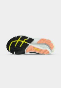 Semelle d’une chaussure de running Brooks montrant un profil en caoutchouc noir, jaune et pêche avec le logo « Brooks », conçue pour l’adhérence et le maintien.