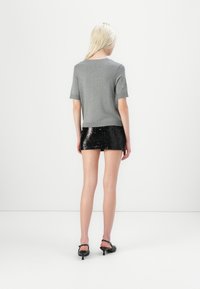 Gray short-sleeve sweater with pearl accents, paired with a black sequin mini skirt, showcasing sleek texture and fitted design.