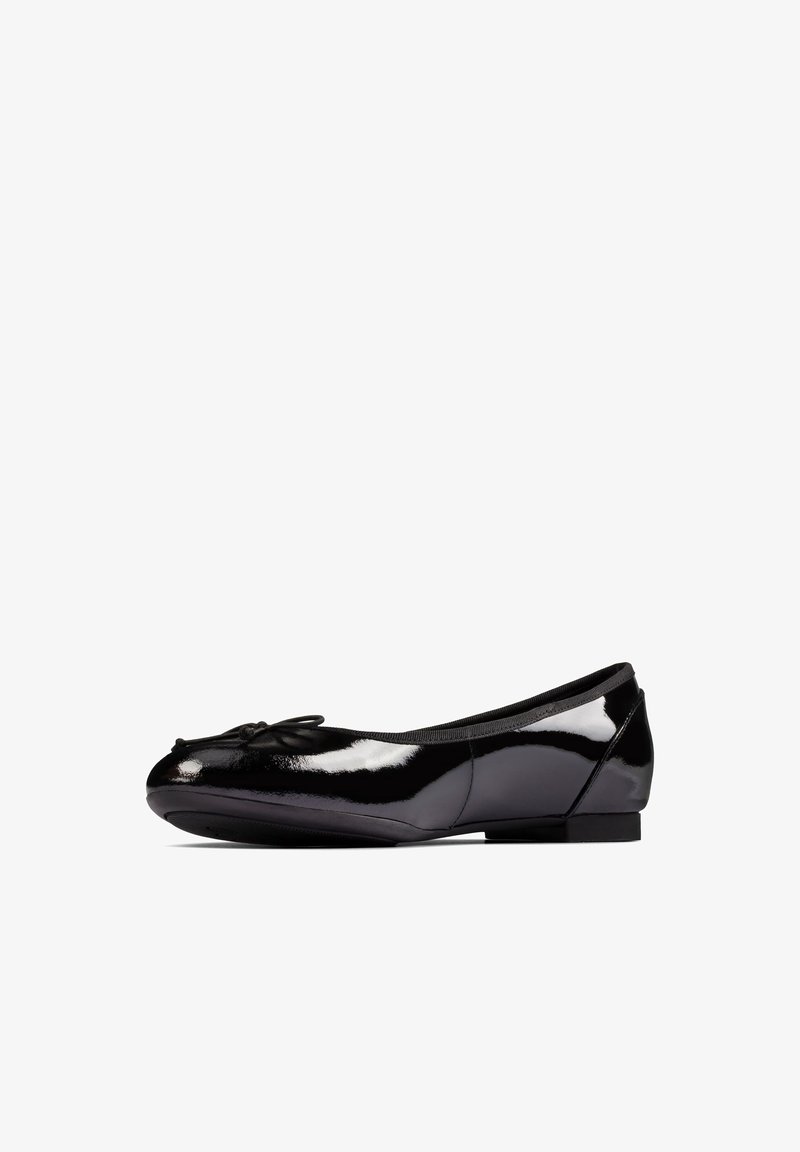 Ballerine en cuir verni noir avec un petit nœud sur l'avant arrondi et un petit talon, vue de profil sur fond blanc.