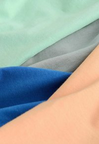 Világoszöld, szürke, kék és barackszínű pamutszövet sima textúrával és egyenletes, puha felülettel.