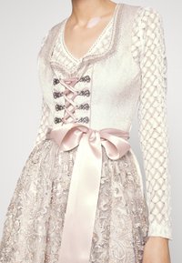 Robe avec un corsage texturé crème à décolleté en V, fermeture lacée sur le devant, et un nœud en satin rose, complétée par une jupe richement brodée.