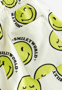 Bawełniane szorty z białym tłem, ozdobione powtarzającymi się żółtymi wzorami uśmiechniętej twarzy oraz napisem "SMILEYWORLD", z elastycznym paskiem w talii i boczną kieszenią.