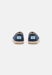 Marine canvas instap schoenen met een geweven jute zool, voorzien van een blauwe TOMS-label aan de achterkant en een afgeronde neus ontwerp.