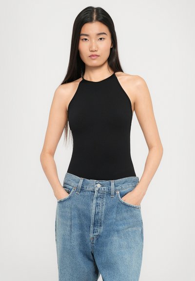 Mustast halter bodysuit'ist, mis on valmistatud venivast kangast, koos kõrge vöökohaga helesiniste teksadega, millel on taskud ja kerge tuhmumine.