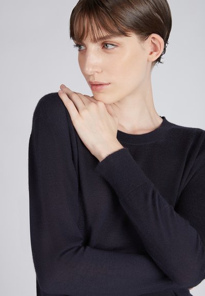 Pull bleu marine à manches longues en tissu doux avec un col rond. Présente des manches ajustées et une texture lisse.