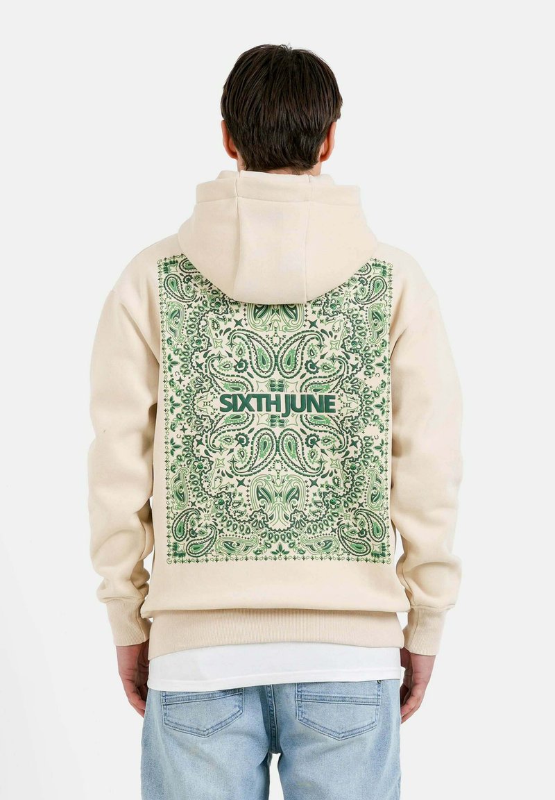 Sudadera beige con un diseño de paisley verde en la parte trasera. Presenta capucha con cordones, puños acanalados y un logo, fabricada con un tejido suave.