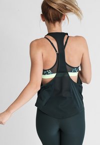 Zwart mouwloos sporttop met racerback ontwerp, voorzien van een mesh rug en een gebogen zoom voor ventilatie en flexibiliteit tijdens trainingen.