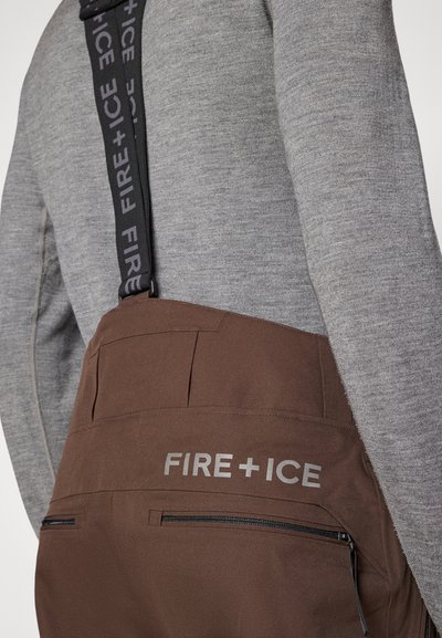 Bruna skidbyxor med justerbara remmar, med frontfickor och tydlig "FIRE+ICE"-branding på baksidan. Mjukt tyg.