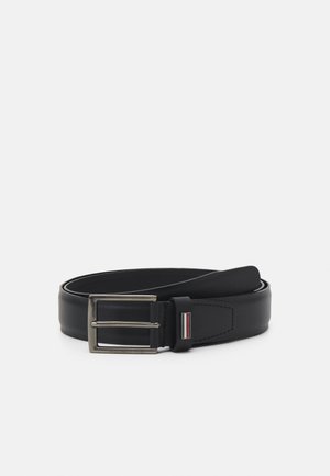 Black leather belt rolled with silver rectangular buckle and small striped detail on belt loop, on white background.