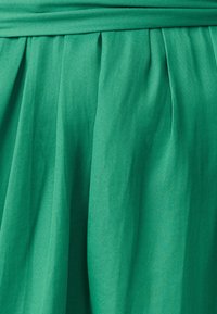 Grüne, plissierte Röcke aus weichem Stoff, mit glatter Textur und einem Bund, der ein fließendes Design erzeugt.