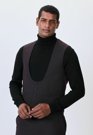Čierny rolák a tmavý vest s hlbokým výstrihom, obsahujúci päť gombíkov a jemné bočné vrecká, hladká textúra, minimálny dizajn.