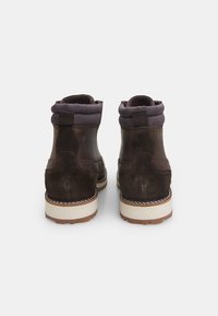 Botas de tobillo de cuero marrón con un acabado texturizado, cuello acolchado en gris y una suela de goma blanca con un patrón de agarre detallado.